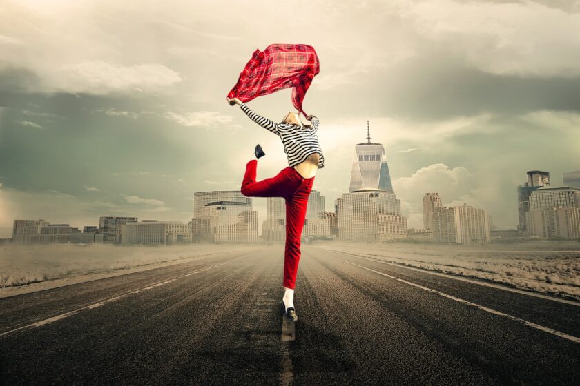 Women in road jumping with glee holding red cloth above her head
